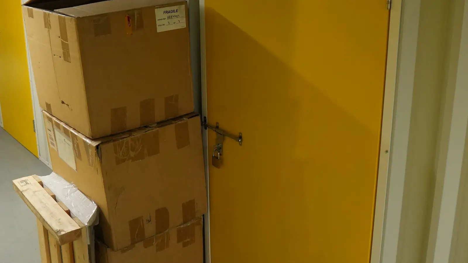Boxes stacked beside a yellow storage unit door at Vachi